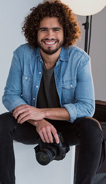 persona sentada en un estudio de fotografía con una cámara en la mano para el Curso de Dirección de Fotografía