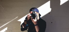 persona con gorra con una cámara en sus manos, preparado para sacar una fotografía