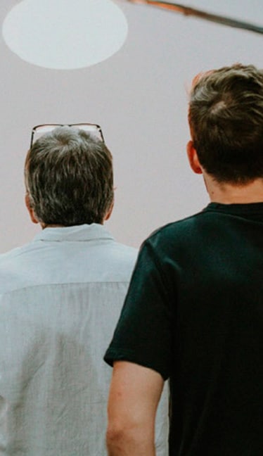 Dos personas observan una escena en un estudio fotográfico blanco con un foco