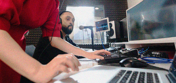 Dos personas en un estudio de grabación con ordenador, monitores y micrófono